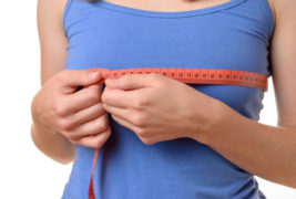 Young woman measuring her breasts